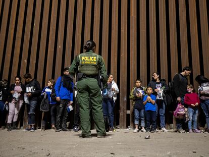 Una oficial de la patrulla fronteriza obseva a un grupo de migrantes detenidos en Yuma, Arizona, el 21 de junio de 2022.