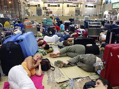 Decenas de personas duermen en el suelo junto a sus maletas en el aeropuerto de El Prat en la noche del viernes tras la cancelación de sus vuelos.