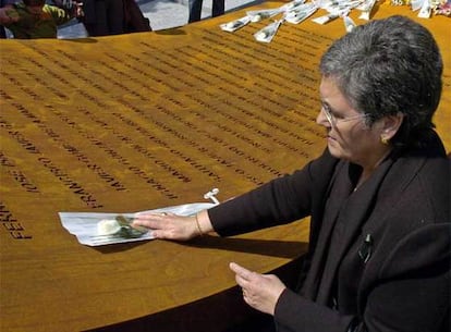 La madre de uno de los fallecidos deposita una flor junto al nombre de su hijo