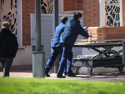 Dos trabajadores trasladan un féretro en el cementerio de La Almudena, en Madrid, el pasado marzo.