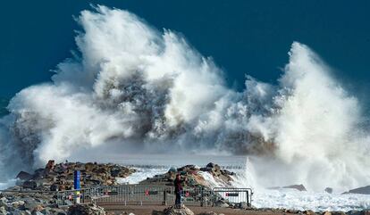 Una persona observa las grandes olas en la playa de la Barceloneta, en Barcelona, por el temporal Gloria.