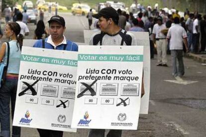 Dos representantes de la organización electoral de Calí informan como votar correctamente durante la jornada de elecciones legislativas de este domingo.