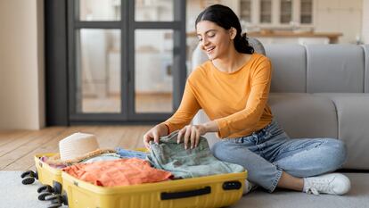 Una chica preparando la maleta en el salón de sus casa