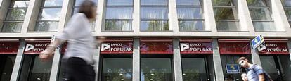 Varios transeúntes pasean frente a una sucursal de Banco Popular en Barcelona.