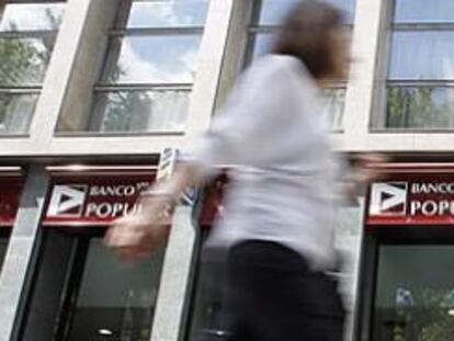 Varios transeúntes pasean frente a una sucursal de Banco Popular en Barcelona.