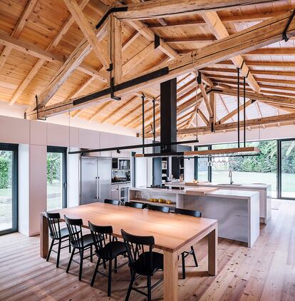 Los típicos rasgos estructurales de una cuadra aún se perciben en el salón con cocina de esta vivienda en Cantabria reformada por Zooco Studio.