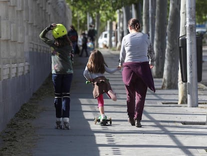 Una mujer pasea con dos niñas en los alrededores de un parque de Madrid.