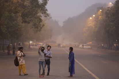 Una joven con mascarilla se toma una fotografía en una calle cubierta de niebla, en Nueva Delhi, el 9 de noviembre de 2017. 