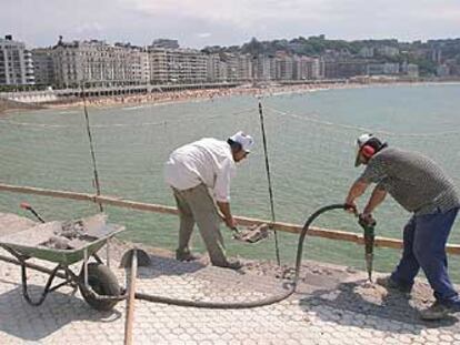 Dos operarios prosiguen, ayer, con la construcción de la barandilla del Paseo de La Concha, tras el fin de la huelga.