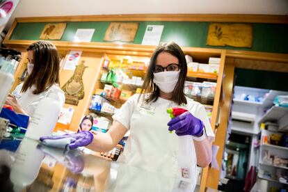 Una farmacéutica desinfecta el mostrador de una farmacia en Granada.