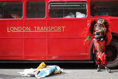 Una artista disfrazada revisa su teléfono mientras espera en el área de preparación antes de su aparición en el principal desfile del carnaval de Notting Hill.