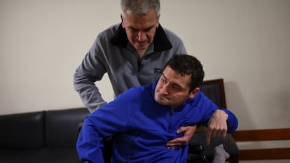 Roman Stavsky, quien ha vivido con encefalitis desde la infancia, recibe ayuda de su padre, Héctor, en su casa de Buenos Aires.