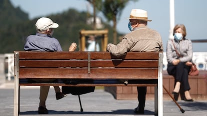 Dos hombres charlan en un banco en San Sebastián.