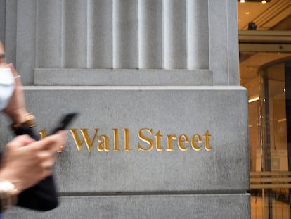 Mulher com máscara passa em frente a um edifício de Wall Street, o centro financeiro de Nova York.