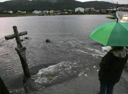 Una vecina observa el cauce del río a punto de desbordarse en la localidad coruñesa de Vimianzo.