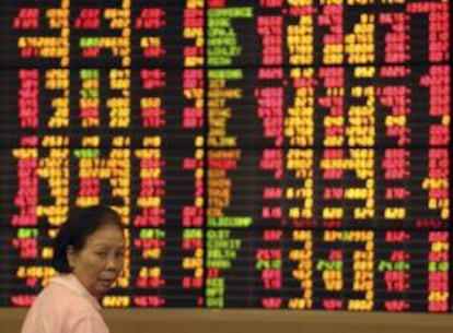 Una mujer pasa junto a un tablero electrónico que muestra los valores de la Bolsa de Valores de Bangkok (Tailandia). EFE/Archivo