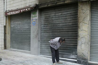 Un hombre mira la persiana de la sede socialista de Sopelana, ennegrecida por la explosión de un artefacto.