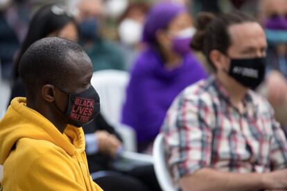 A la izquierda, el 'número nueve' de las listas de Unidas Podemos a la Asamblea de Madrid, Serigne Mbayé, durante el mitin de Usera.