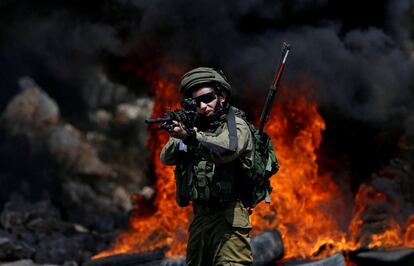 Un soldado israel camina apuntando con su arma a palestinos que se manifiestan en la localidad de Kofr Qadom, cerca de Nablus (Palestina).