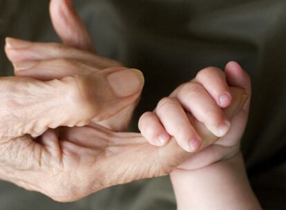 Una niña  agarra con fuerza la mano de su bisabuela.