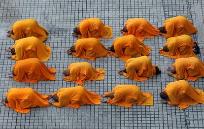 Monjes budistas se postran mientras realizan la ceremonia de 'tres pasos un arco' en el Monasterio Kong Meng San Phor Kark, en la víspera del día de Vesak en Singapur.