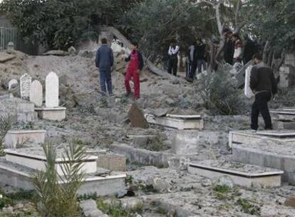 Un grupo de palestinos observa los daños que ha dejado el bombardeo en el principal cementerio de la ciudad de Gaza.