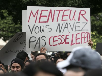 Un ciudadano sostiene una pancarta durante la protesta donde se puede leer "Menteur, vous n'avez pas cessé lefeu" ("Mentiroso, usted no paró el fuego").