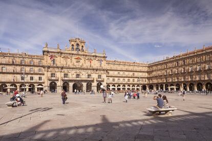 Aunque sobre gustos no hay nada escrito, muchos dicen que es la plaza más bonita de España. Y méritos acumula de sobra. Por la noche, con los edificios barrocos del siglo XVIII magníficamente iluminados (por ejemplo, el ayuntamiento, con sus cinco arcos de granito y su campanario), es fácil estar de acuerdo con la afirmación. De hecho, en ese momento parece la plaza más bonita del mundo. Pero esta amplia superficie, que solo se rodeó con el complejo de edificios del arquitecto barroco Alberto de Churriguera (1676-1750) a partir de 1724, también debe visitarse de día: estar al sol, verse con amigos, tomar un café, hacer negocios, ir de compras, oír música… Una plaza siempre llena de estudiantes de su famosa universidad —que tras Bolonia y Oxford es la más antigua de Europa—, de turistas apreciando los edificios y de parejas paseando bajo los soportales. <a href="https://elviajero.elpais.com/elviajero/2018/10/18/actualidad/1539853165_052605.html" target="_blank">La vida de Salamanca palpita en torno a su plaza</a>. Como hace siglos.