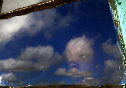 Anda, un ni&ntilde;o de la localidad de Qunu mira desde el interior de la choza en que vive hacia el lugar donde tendr&aacute; lugar el entierro de Nelson Mandela. 