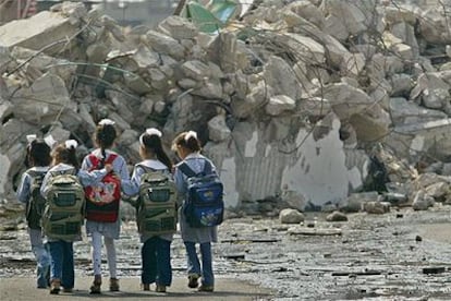 Cinco escolares palestinas caminan por delante de un edificio destruido en el campo de Yabalia, al norte de Gaza.
