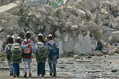 Cinco escolares palestinas caminan por delante de un edificio destruido en el campo de Yabalia, al norte de Gaza.