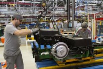 Dos operarios colocan hoy las bater&iacute;as de la furgoneta el&eacute;ctrica Citro&euml;n Berlingo en la cadena de montaje de la planta de PSA.