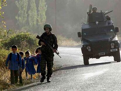 Un soldado turco, protegido por un vehículo blindado, conversa ayer con unos escolares durante una patrulla cerca del pueblo de Uludere.