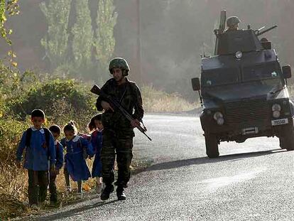 Un soldado turco, protegido por un vehículo blindado, conversa ayer con unos escolares durante una patrulla cerca del pueblo de Uludere.