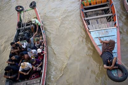 Dos barcos llenos de pasajeros se cruzan en el río. This photo taken on July 1, 2015 shows people riding on a small ferry boat at a jetty in Yangon.