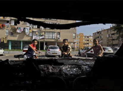 Tres niños miran un coche arrasado tras los disturbios registrados entre árabes y judíos en la ciudad de Acre el 12 de octubre.