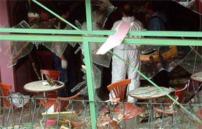 Expertos de la policía forense turca examinan los daños causados en el interior del café en Ankara.