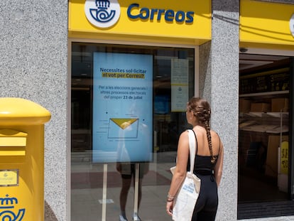 Una mujer observa un cartel de información en una oficina de Correos de Menorca.