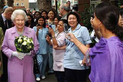 Empleadas del Royal London Hospital fotografían a la reina Isabel II ayer durante su visita.