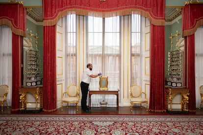 Un trabajador limpia uno de los objetos decorativos del pasillo principal del palacio de Buckingham.