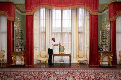 Un trabajador limpia uno de los objetos decorativos del pasillo principal del palacio de Buckingham.