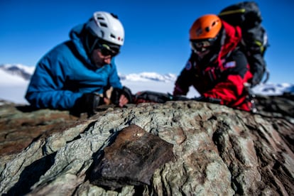 El biólogo Jorge Gallardo recoge sedimentos en el pico Charles junto al explorador Juan Pablo Muñoz. En primer plano, una roca con líquenes.