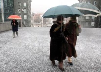 Dos mujeres caminan por una calle de Bilbao protegiéndose del intenso frío.
