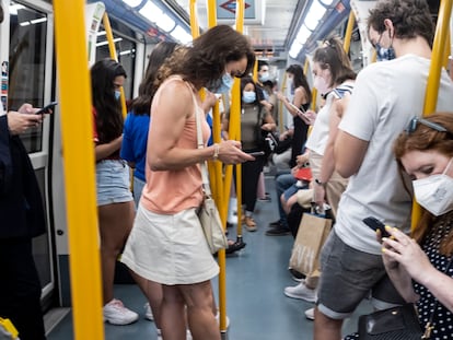 Un grupo de personas consulta sus teléfonos móviles en un vagón del metro de Madrid.