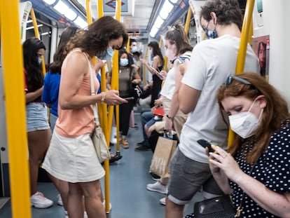 Personas consultan sus teléfonos móviles en un vagón del metro de Madrid.