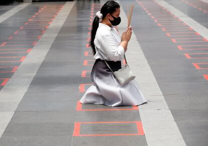 Una mujer reza a la deidad hindú Ganesha, dios de las Artes y las Ciencias, sobre una marca para mantener la distancia social en un centro comercial de Bangkok (Tailandia) este martes. Tras dos meses sin transmisión local de coronavirus, Tailandia es uno de los países que ha conseguido, hasta el momento, contener la pandemia.