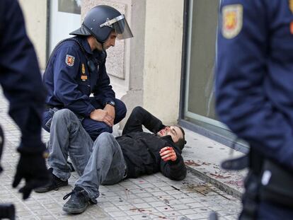Un agente del Cuerpo Nacional de Policia atiende a un joven herido en uno de los enfrentamientos entre manifestantes y policía en el centro de Valencia.