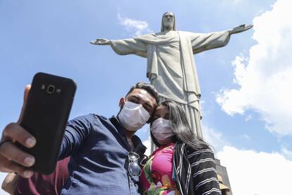 Turistas no último dia 13 tiram foto no Cristo Redentor, usando máscaras.