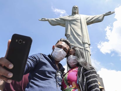 Turistas no último dia 13 tiram foto no Cristo Redentor, usando máscaras.