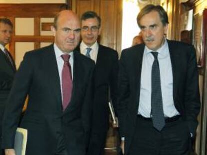 El ministro de Economía y Competitividad, Luis de Guindos (i), acompañado por el portavoz de Economía del PSOE, Valeriano Gómez (d), tras sus respectivas intervenciones en el seminario "Competitividad y Marca España" que se celebra esta semana en la Universidad Internacional Menéndez Pelayo.